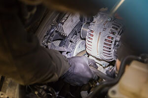 mechanic working on engine near alternator