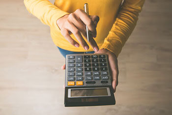 a person in a yellow sweater holding a calculator