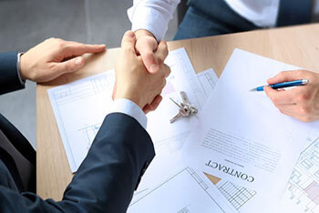 two people shake hands after signing the contract